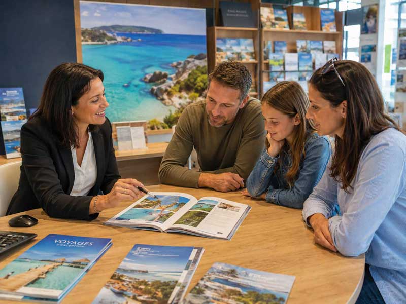 Famille en agence de voyages physique échangeant avec une conseillère pour préparer son séjour
