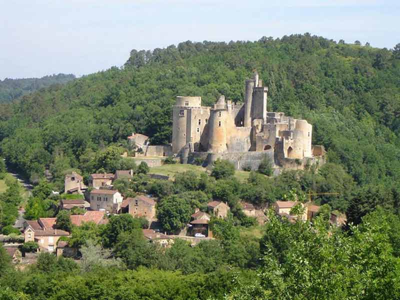 Vue aérienne du château de Bonaguil entouré de forêts, surplombant le village médiéval dans le Lot-et-Garonne