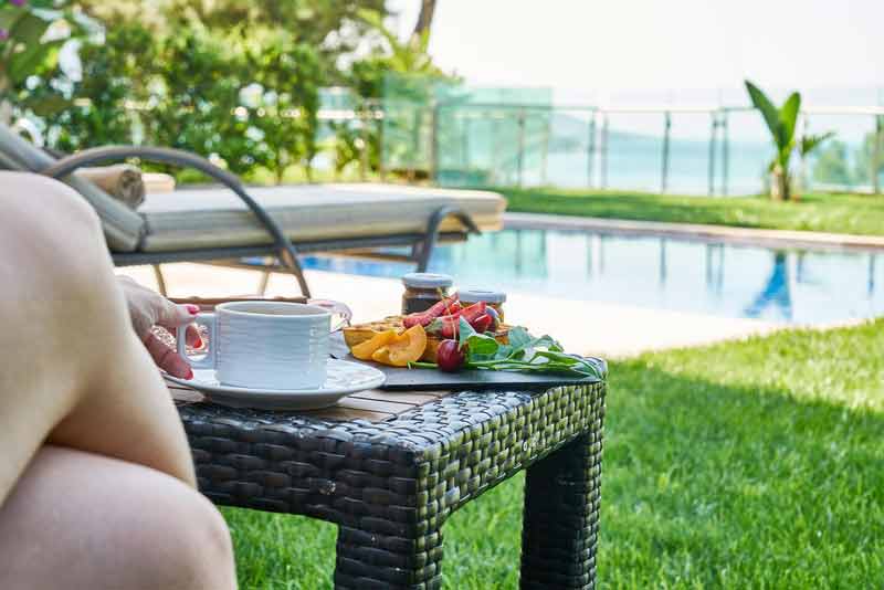 Petit-déjeuner servi en extérieur près d’une piscine dans le jardin d’un gîte