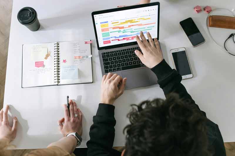 Réunion de travail avec planification sur ordinateur portable et agenda papier