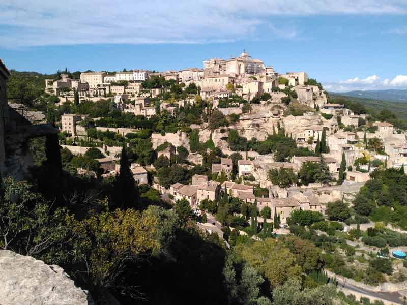 Vue panoramique du village perché de Gordes dans le Luberon, avec ses maisons en pierre et ses terrasses verdoyantes
