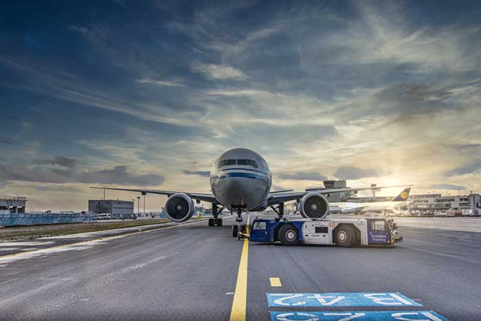 photo d'un avion tracté par un véhicule de remorquage spécialisé (pushback tug) sur la piste de décollage d'un aéroport