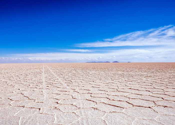 Paysage aride et tendu du Salar d'Uyuni en Bolivie, avec son sol craquel de sel sous un ciel bleu clatant