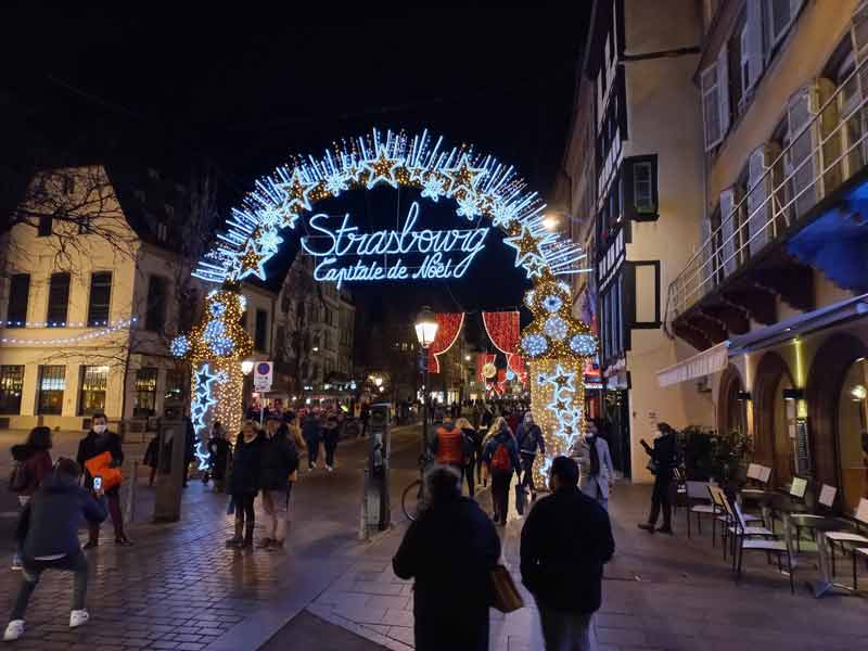 Arche lumineuse « Strasbourg Capitale de Noël » à l’entrée d’une rue piétonne du centre historique, illuminée pour les marchés de Noël en décembre
