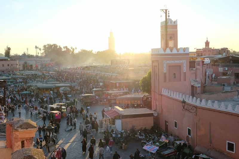 Place Jemaa el-Fna animée au coucher du soleil à Marrakech, avec le minaret de la Koutoubia en arrière-plan, pour un week-end au soleil en décembre