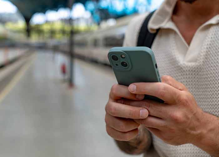 Voyageur consultant son t�l�phone sur un quai de gare avant de r�server un train Paris-Lyon