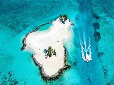 photo aérienne d'une petite île des Maldives avec un bateau dans une passe