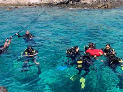 groupe de plongeurs équipés de bouteilles d'oxygène, de masques, de tubas et de palmes qui discutent à la surface de la mer, îles Lavezzi (Corse)