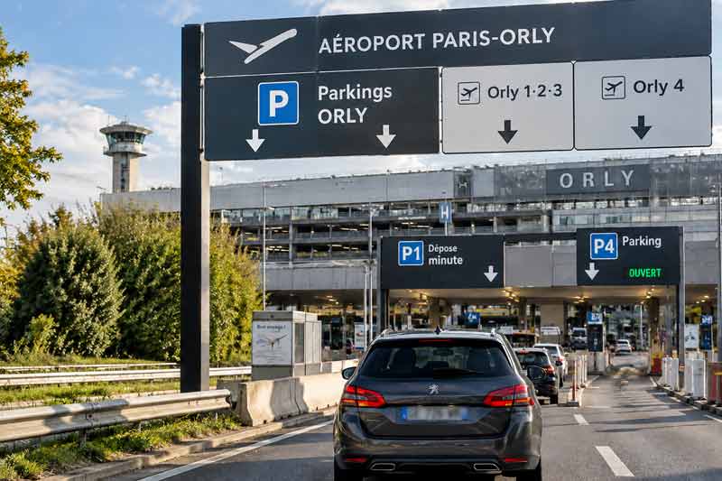 Panneaux de signalisation vers les parkings et terminaux de l'aéroport Paris-Orly avec voitures en approche