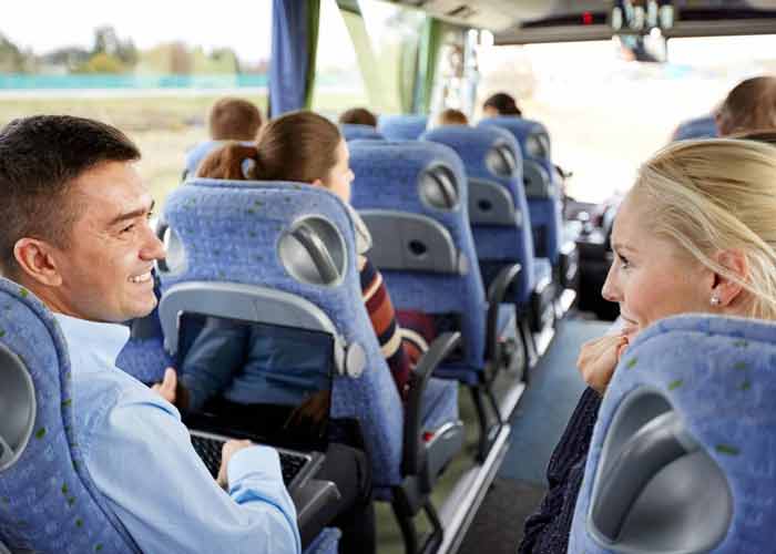 Voyageurs souriants discutant � bord d'un autocar aux si�ges bleus confortables lors d'un transfert de groupe en autocar