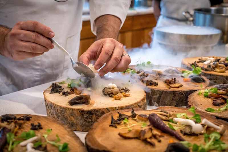 Chef d’un restaurant écolo qui prépare des légumes qui vont être servis sur des morceaux de bois