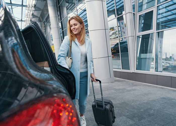 Voyageuse avec sa valise montant dans sa voiture de location � l'a�roport P�le Cara�bes en Guadeloupe