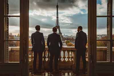 3 hommes d'affaires regardent la tour Eiffel depuis leur salle de réunion (Paris, France)