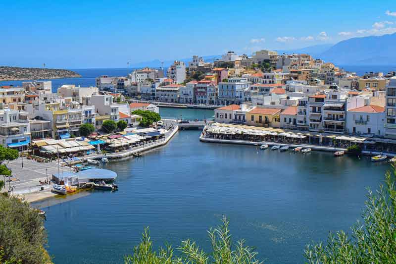 Vue panoramique sur le port pittoresque d'Agios Nikolaos en Crète, avec ses maisons colorées, ses terrasses de cafés au bord
de l'eau et la mer Égée en arrière-plan