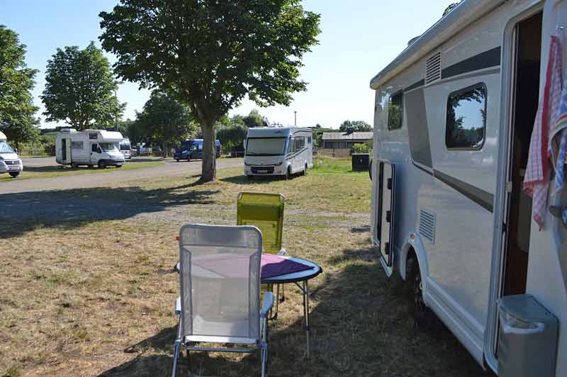 Camping-cars stationnés sur une aire dédiée avec table et chaises installées devant