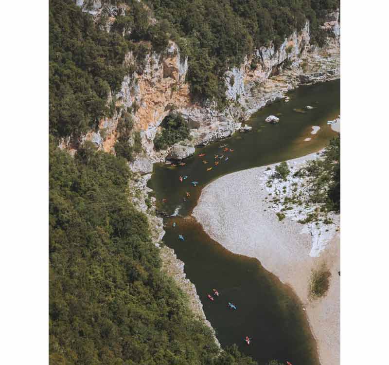 Vue aérienne de kayakistes descendant les gorges de l'Ardèche entre falaises calcaires et plage de galets, Ardèche, 
							France