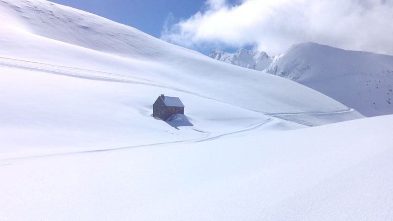 Petite cabane en pierre isolée au milieu d'un vaste manteau neigeux immaculé, avec des traces de ski sillonnant les pentes pyrénéennes, 
							Pyrénées, France