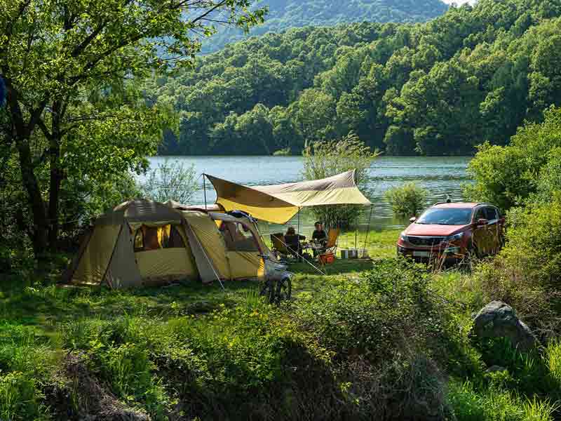 Grande tente familiale dans une forêt au bord d'un lac