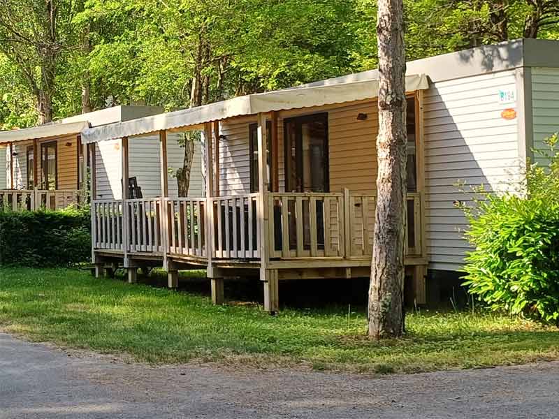 Alignement de mobil-homes avec terrasse dans un camping au cœur de la nature