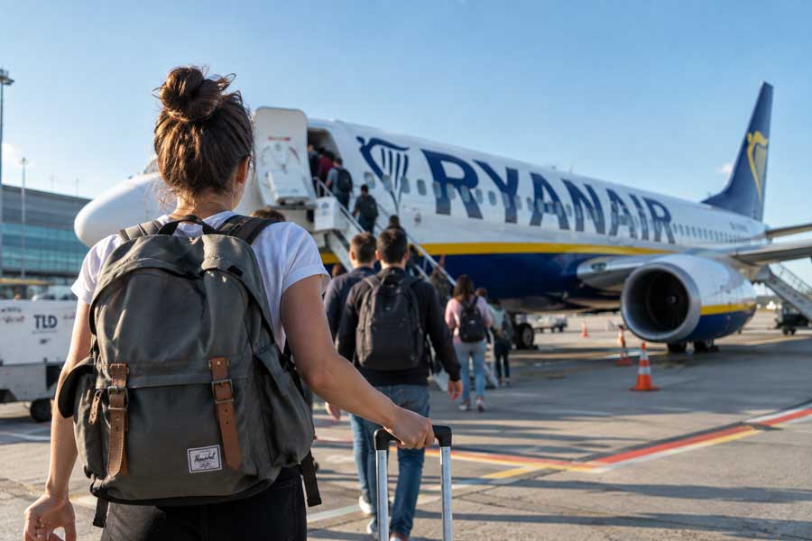 Embarquement à pied vers un avion Ryanair sur le tarmac, voyageurs avec sacs à dos et valises cabine