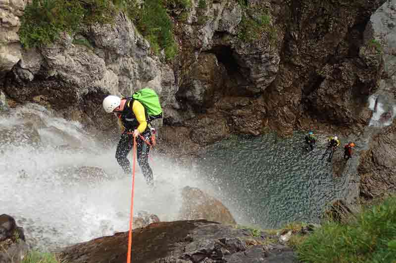 Descente en rappel dans une cascade lors d’une sortie canyoning, une activité aquatique à sensations fortes