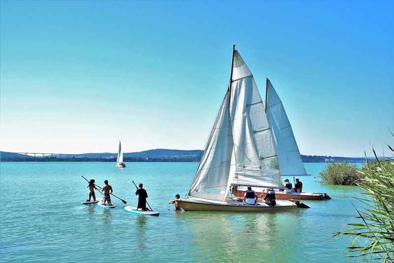 groupe d'amis qui font du paddle et du catamaran sur un lac lors d'un week end sportif