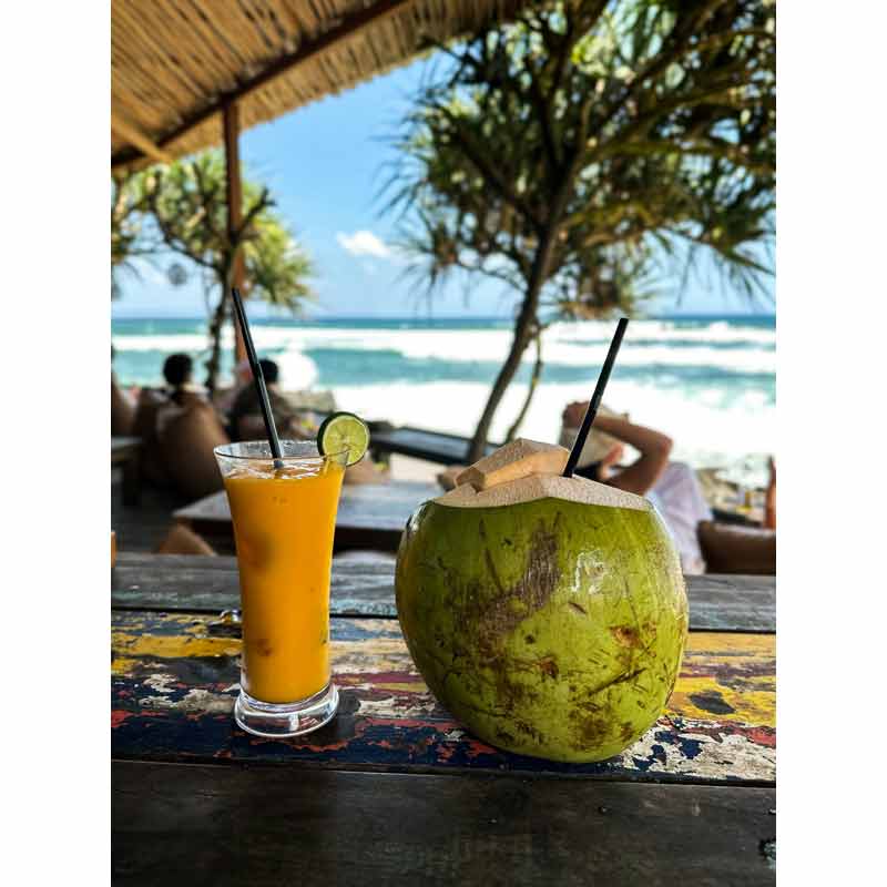 boisson à la mangue et noix de coco fraîche sur une plage de Bali, avec vue sur l’océan et palmiers
