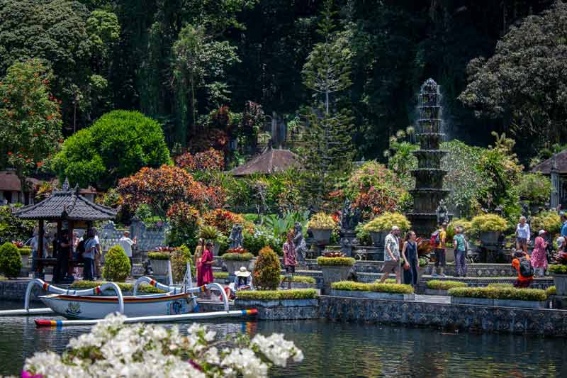 jardins aquatiques de Tirta Gangga à Bali, avec ses bassins, statues, végétation tropicale et visiteurs se promenant autour des fontaines