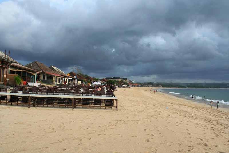 plage de Jimbaran à Bali avec ses restaurants de poissons en bord de mer et ses tables installées sur le sable avant l’orage