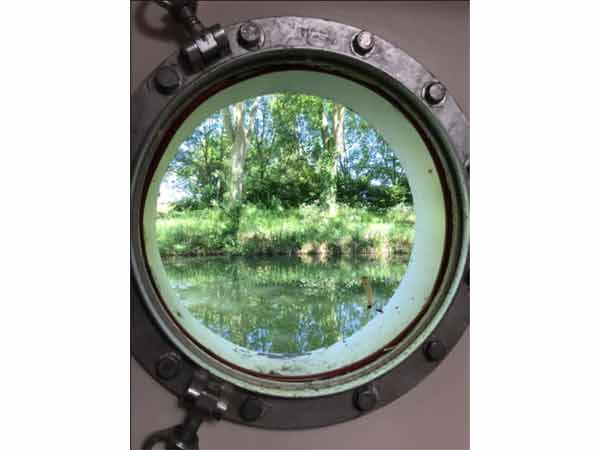 Vue sur la nature invironnante depuis le hublot d'une péniche à Toulouse, France