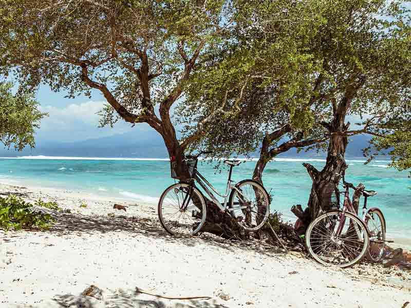 Couple qui a posé 2 vélos au bord d'une plage à Bali