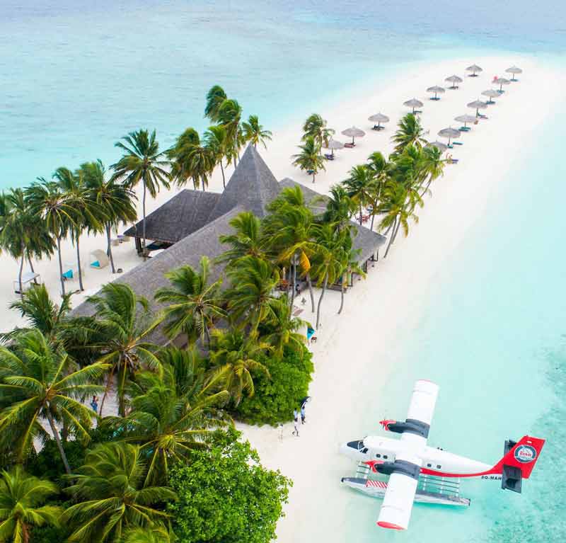Avion qui attend un groupe devant un hôtel sur la plage d’une île paradisiaque