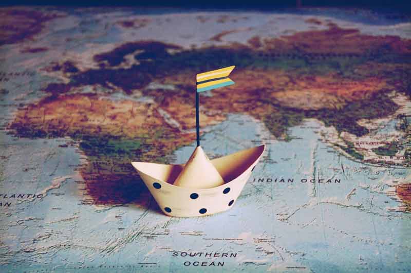 carte du monde avec un bateau en papier posé dessus