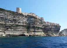 Falaises de Bonifacio en Corse, avec les maisons perchées au sommet, vues depuis la mer sous un ciel bleu éclatant