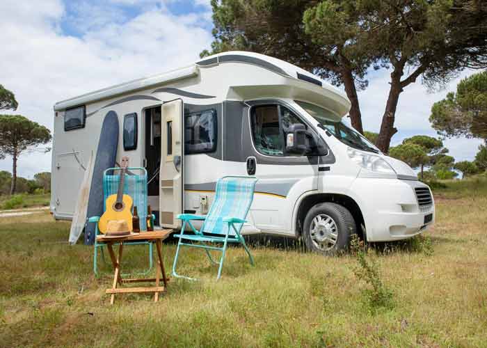 Camping-car profil� stationn� dans la nature avec chaises de camping et guitare devant