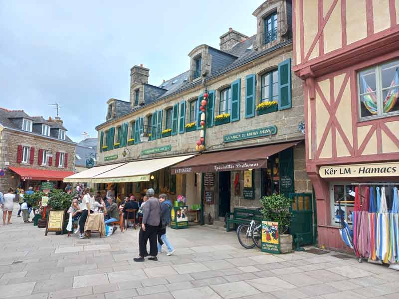 Rue piétonne animée de Concarneau, avec ses façades en pierre et à colombages, terrasses de café et boutiques typiques