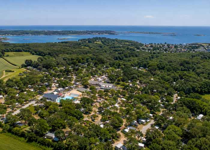 Vue a�rienne d'un camping breton avec piscine, nich� dans la verdure � proximit� du littoral et des �les