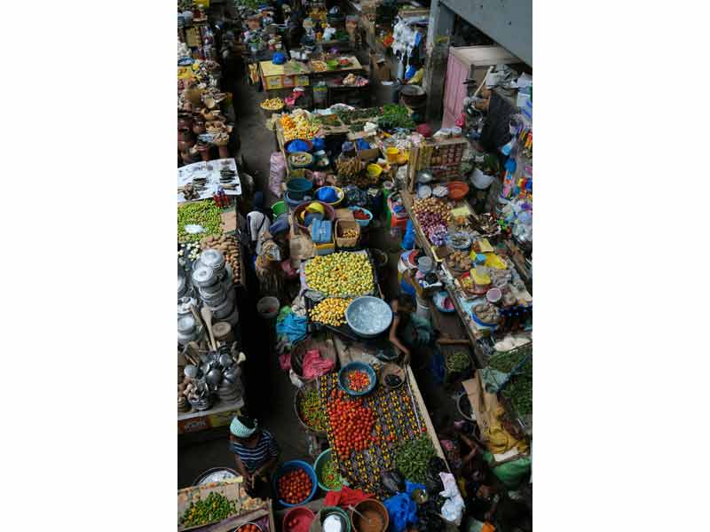 Marché local à Abidjan en Côte d’Ivoire, avec étals colorés de produits frais, fruits tropicaux et artisanat