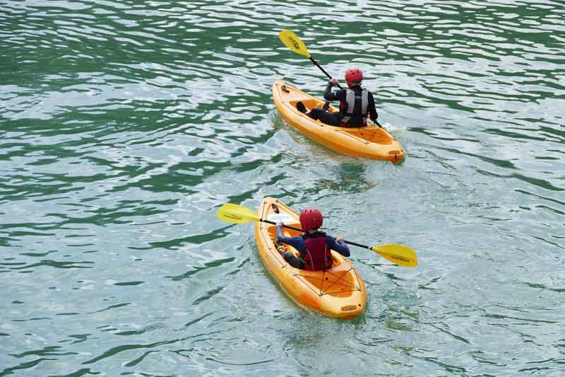 Deux enfants casqués et équipés de gilets de sauvetage pagaient en kayak jaune sur la Dordogne