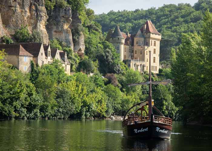 Gabarre traditionnelle naviguant sur la Dordogne au pied du ch�teau de la Malartrie et des maisons troglodytiques de La Roque-Gageac