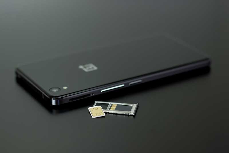 Smartphone noir posé à plat avec son tiroir SIM éjecté et une carte SIM physique à côté, illustrant le passage de la carte SIM traditionnelle
à l'eSIM