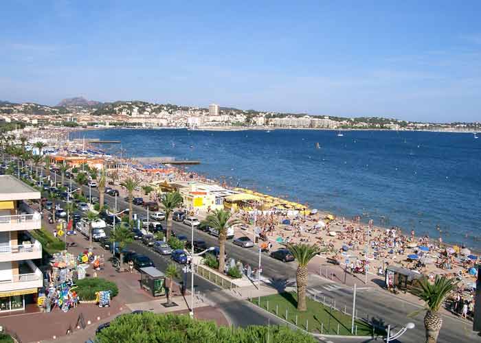 Vue panoramique de la plage de Frjus, borde de palmiers avec la mer Mditerrane et des collines en arrire-plan