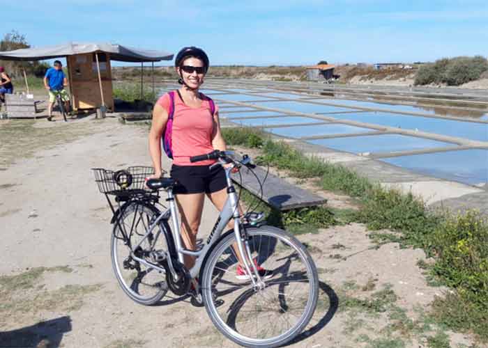 Cycliste souriante posant devant les marais salants de Loix sur lle de R, symbole dun tourisme nature et  vlo