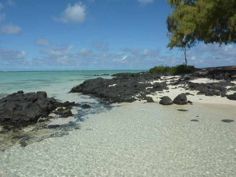 Plage de l’île Maurice avec sable clair, roches volcaniques noires et lagon turquoise