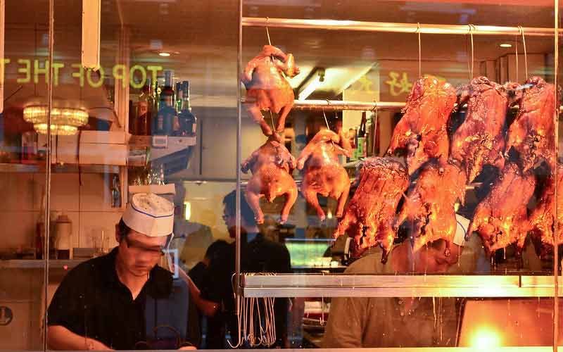 Photo de la cuisine d'un restaurant dans le quartier chinois de Londres (Chinatown) avec des poulets suspendus