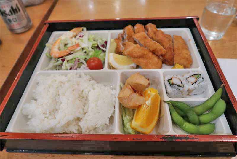 Plateau contenant de la salade et du riz, des sushis et du poulet dans un restaurant du quartier chinois (Chinatown) de Londres (cité de Westminster)