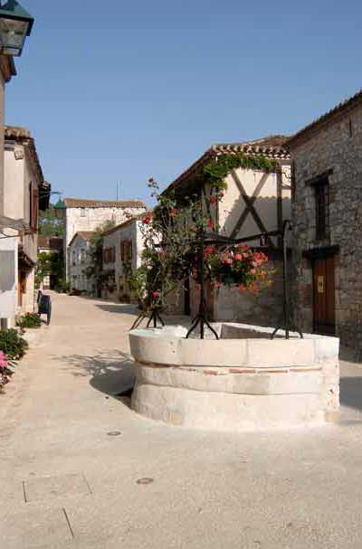 Puits en pierre fleuri au cœur du village médiéval de Pujols, classé parmi les Plus Beaux Villages de France dans le Lot-et-Garonne