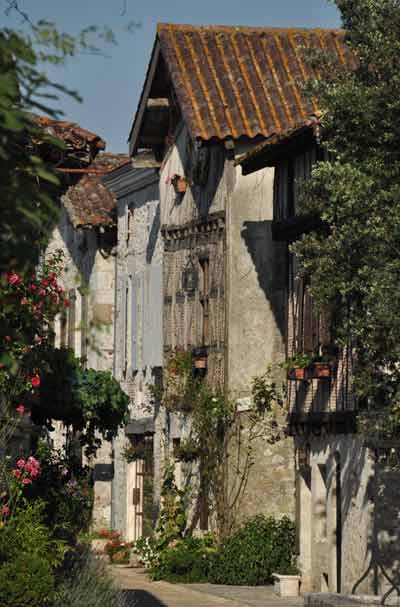 Maisons médiévales en pierre et colombages dans une ruelle fleurie du village de Pujols, dans le Lot-et-Garonne