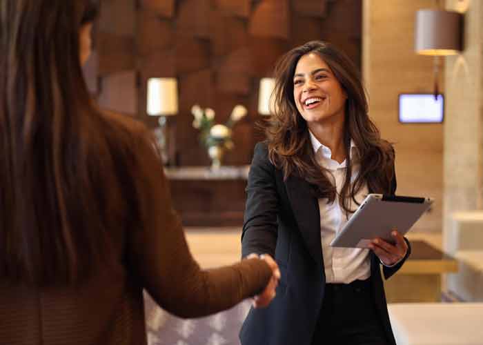 Accueil chaleureux dans un htel, une rceptionniste souriante serrant la main d'une cliente