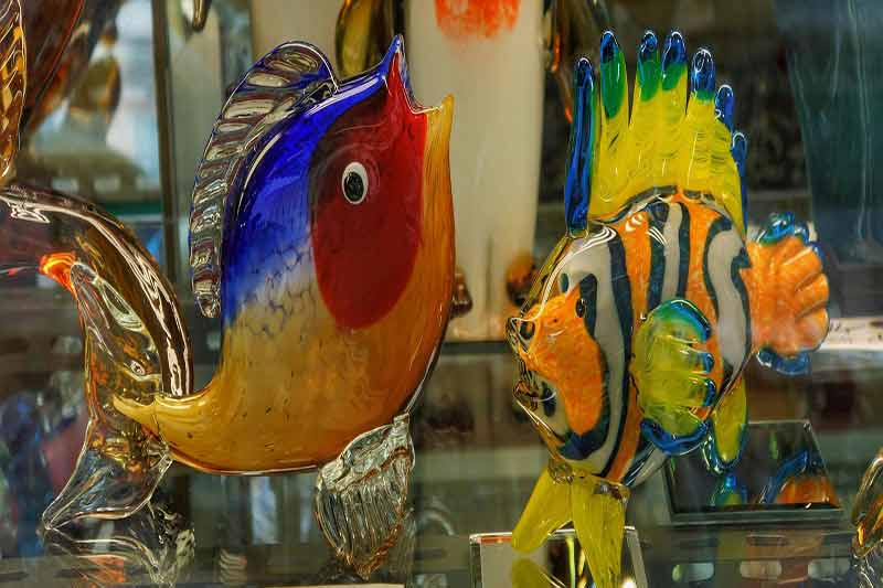 Poissons en verre soufflé de Murano aux couleurs vives exposés dans une vitrine à Venise